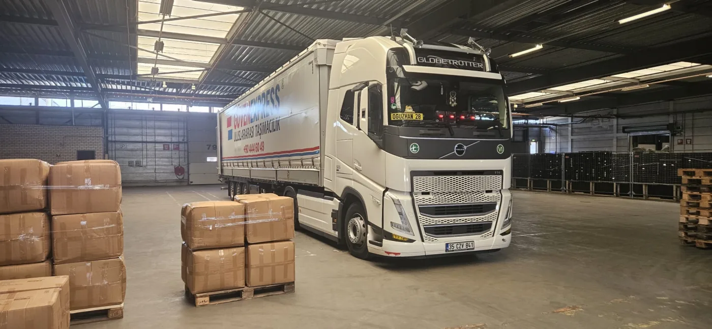 Palletized cartons prepared beside a GüvenExpress vehicle in a warehouse