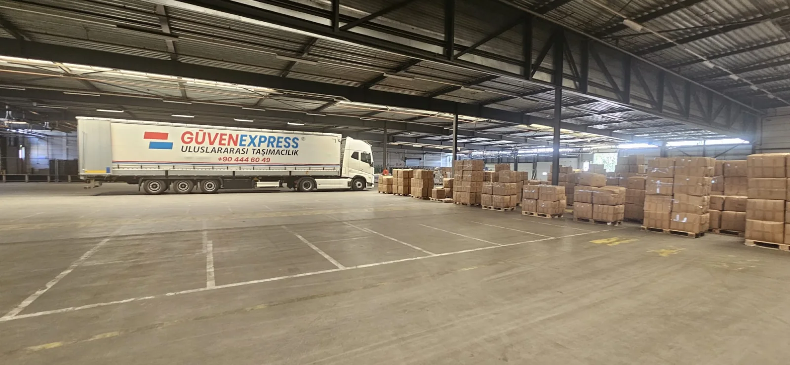 GüvenExpress truck beside palletized goods inside an İzmir warehouse